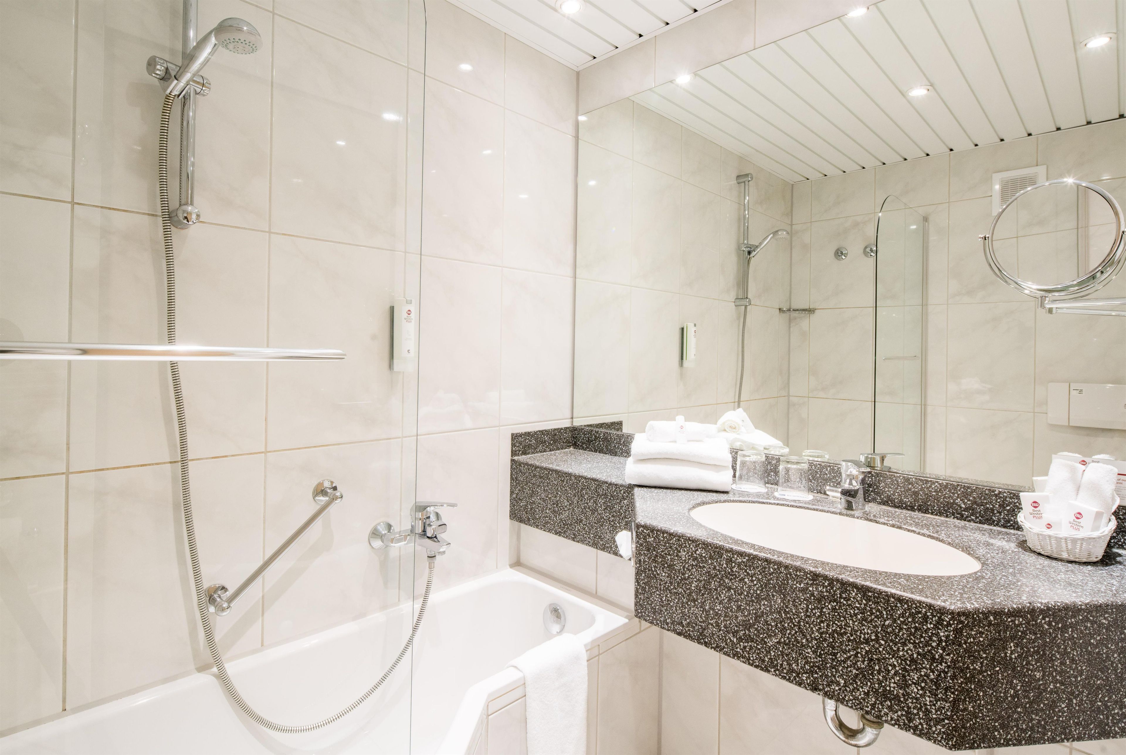 Ein modernes Badezimmer mit Badewanne, Dusche, Waschtisch und einem großen Spiegel.