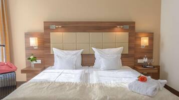 Habitación de hotel con una cama grande, dos mesitas de noche y cabecera con iluminación integrada.
