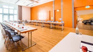 Une salle de conférence avec de longues tables, des chaises et une voiture garée à l’extérieur.