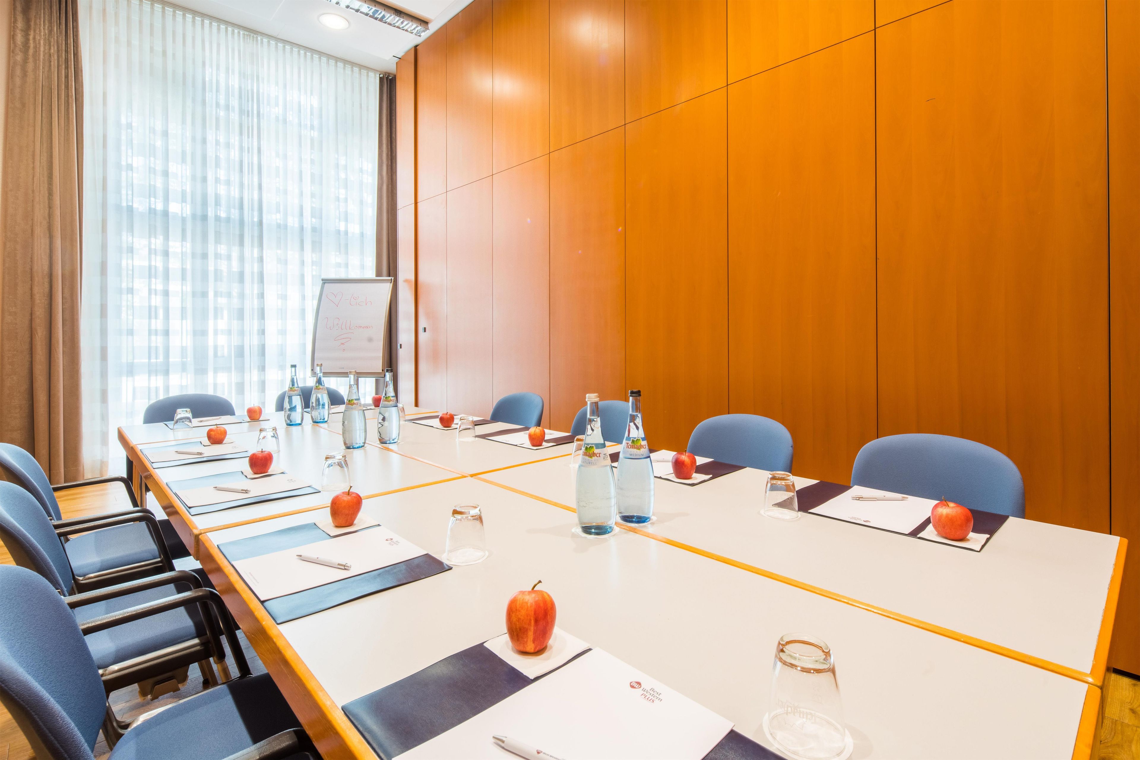 A conference room with a long table, chairs, water bottles, apples, and a whiteboard.