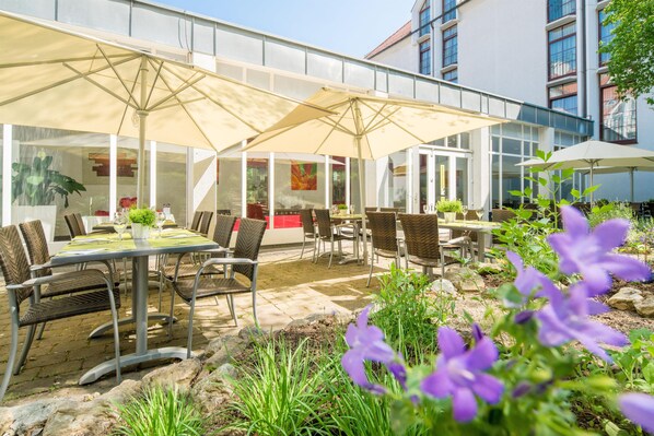 An outdoor patio with tables and chairs, large umbrellas, and a view of a building with large windows. - Best Western Plus Hotel Am Schlossberg (Nuertingen)