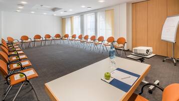 Un salón de conferencias con una larga mesa, varias sillas, una pizarra y un proyector.