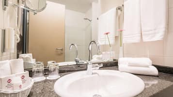Un baño de hotel con un lavabo grande, espejo y toallero.