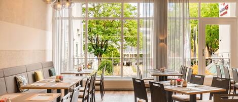 Un comedor moderno con ventanas amplias, mesas y sillas de madera.