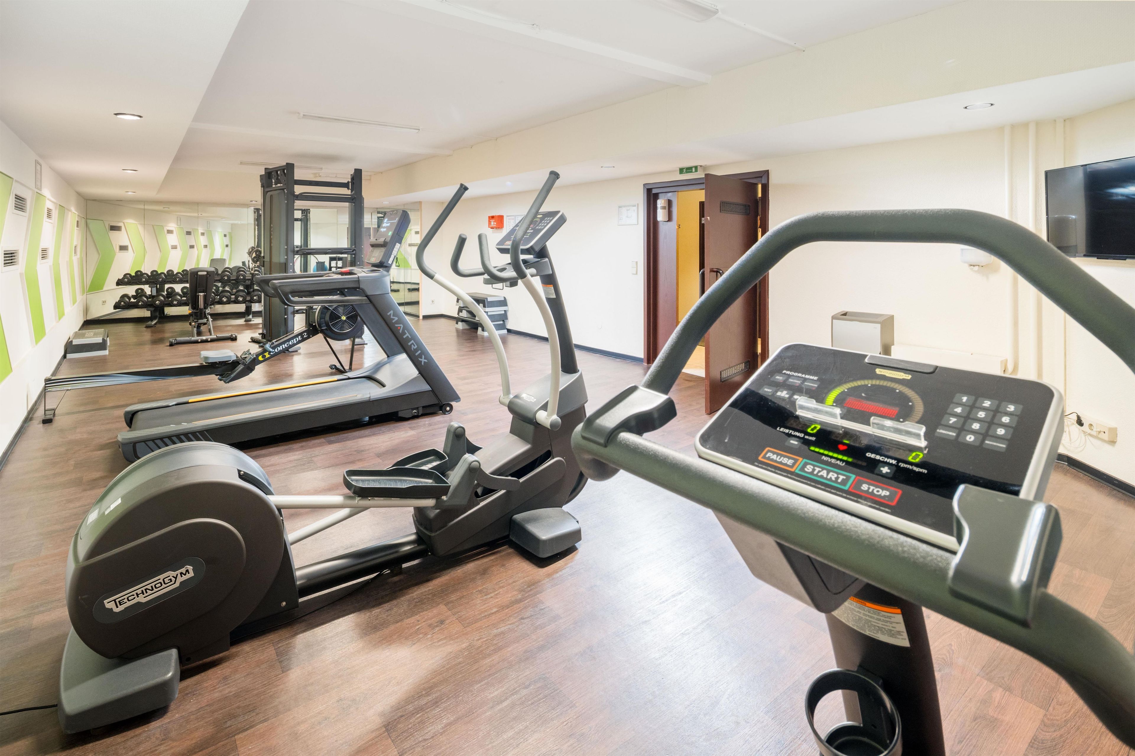 A gym with various exercise equipment including treadmills, a stationary bike, and weight machines.