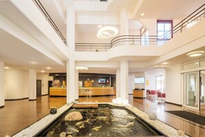 A hotel lobby with a reception desk, a water feature, and a second-floor balcony. - Best Western Plus Hotel Am Schlossberg (Nuertingen)