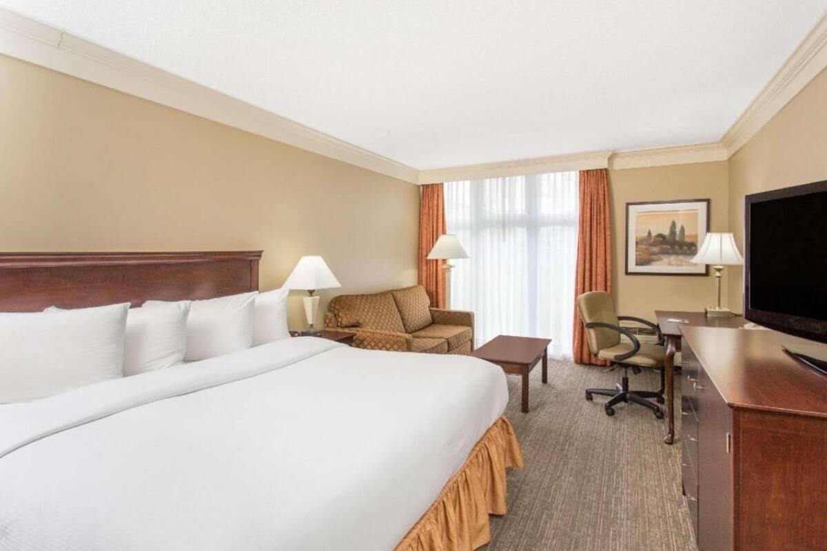 Una habitación de hotel con una cama grande, un sofá, un escritorio, una silla y una televisión.
