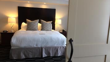 A hotel room with a large bed, two bedside lamps, a headboard, a bedside table with a phone, and a patterned carpet.