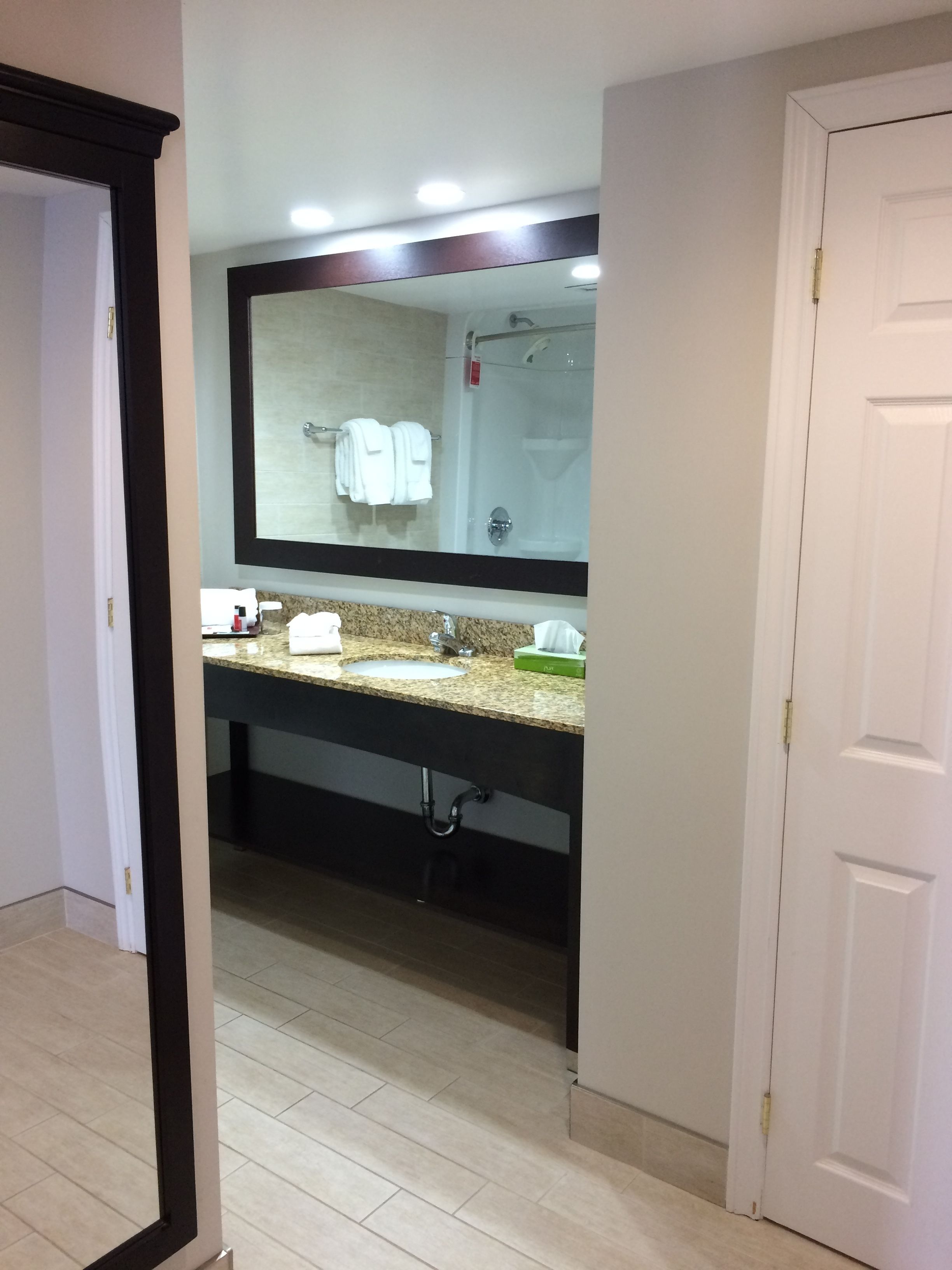 A bathroom with a large mirror, a sink, and a shower.