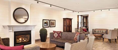 A spacious living room with a fireplace, multiple seating areas, and a large mirror on the wall.