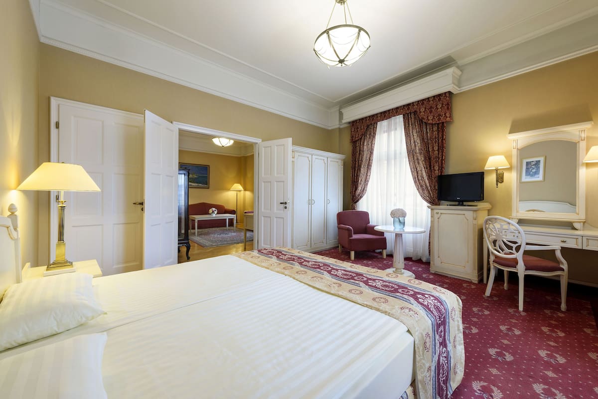 Een hotelkamer met een groot bed, een bureau, een stoel, een televisie en een kledingkast.