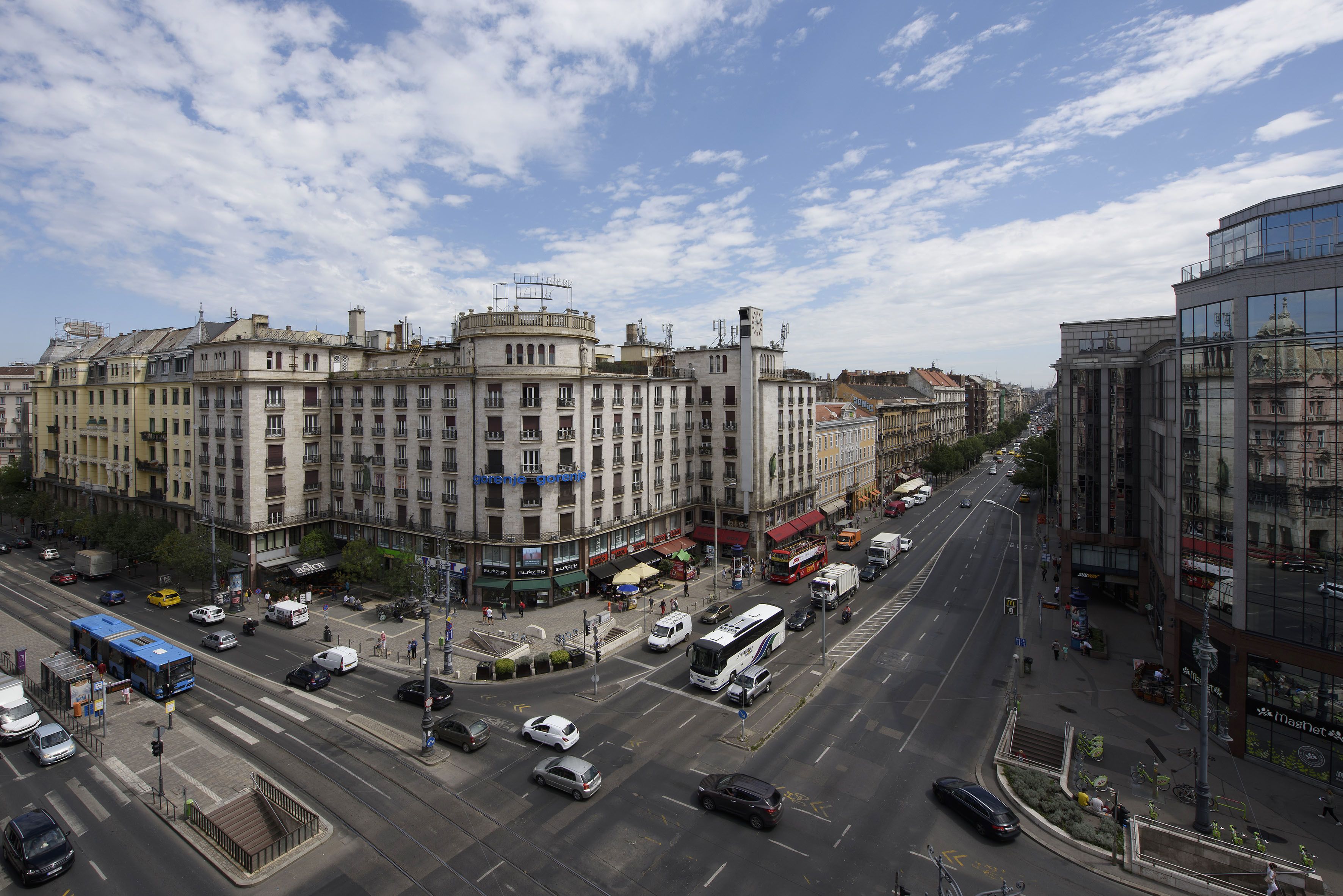 A city street with buildings, vehicles, and a bus.