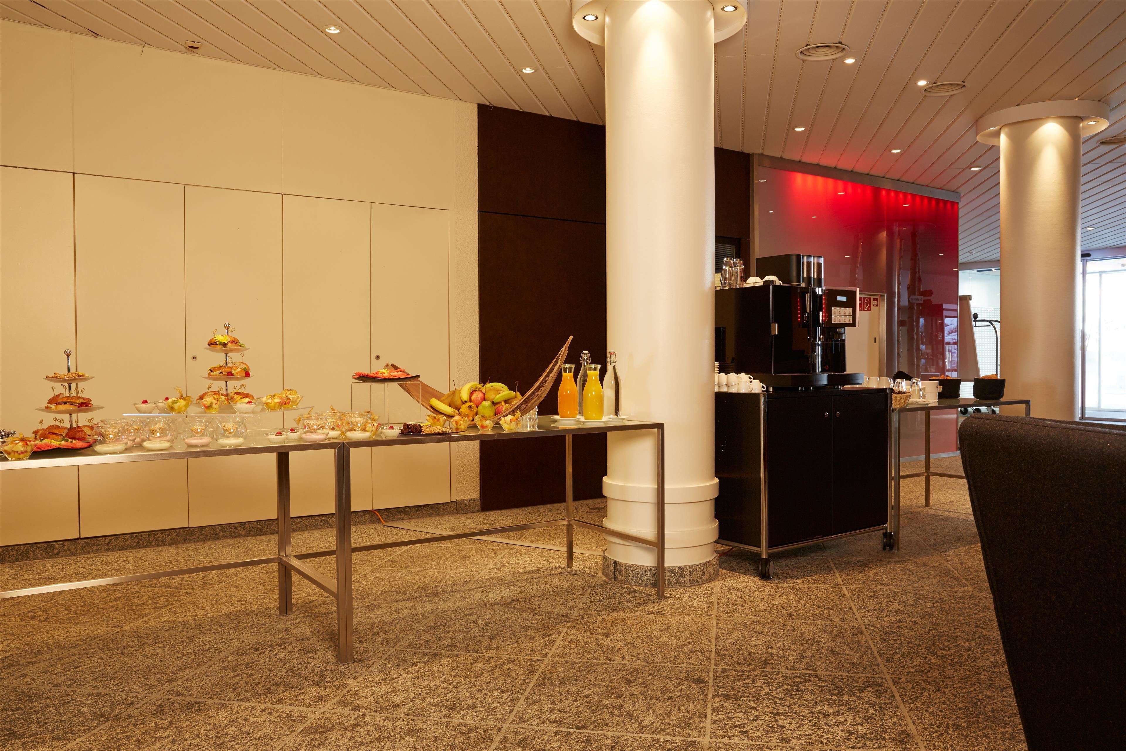 A buffet setup with various food items and beverages, a coffee machine, and a seating area.