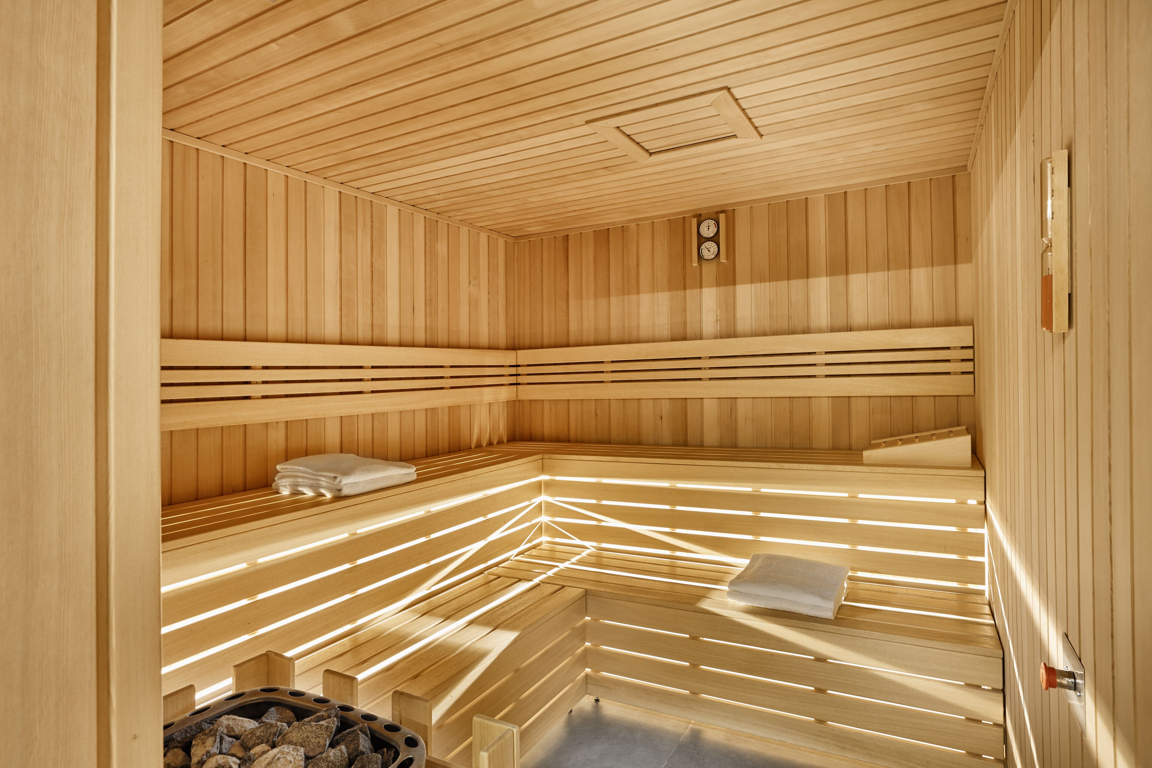 Un sauna avec des parois et des bancs en bois, une horloge et un porte-serviettes.