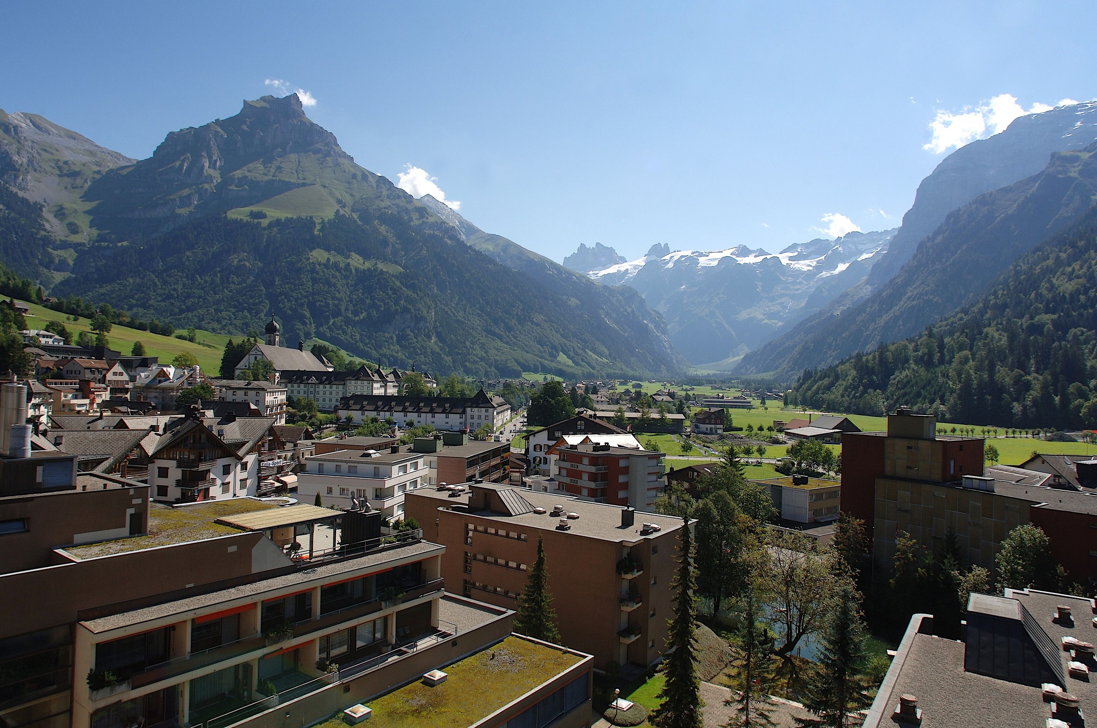 A mountainous town with modern buildings, a church, and a valley.