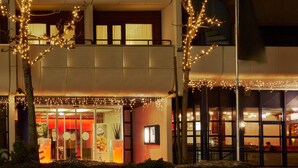 A hotel with a modern design, featuring a glass facade, outdoor seating area, and decorative lighting. - Hotel Regina Titlis, a Trademark Collection by Wyndham (Engelberg)