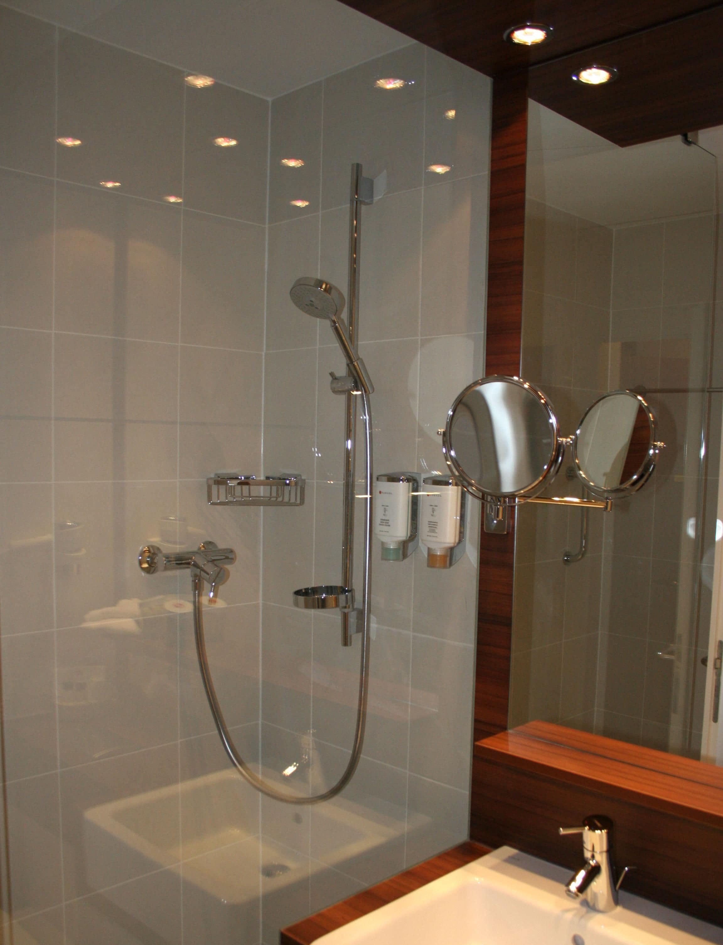 Une salle de bain moderne avec une douche à parois de verre, un lavabo et un miroir.