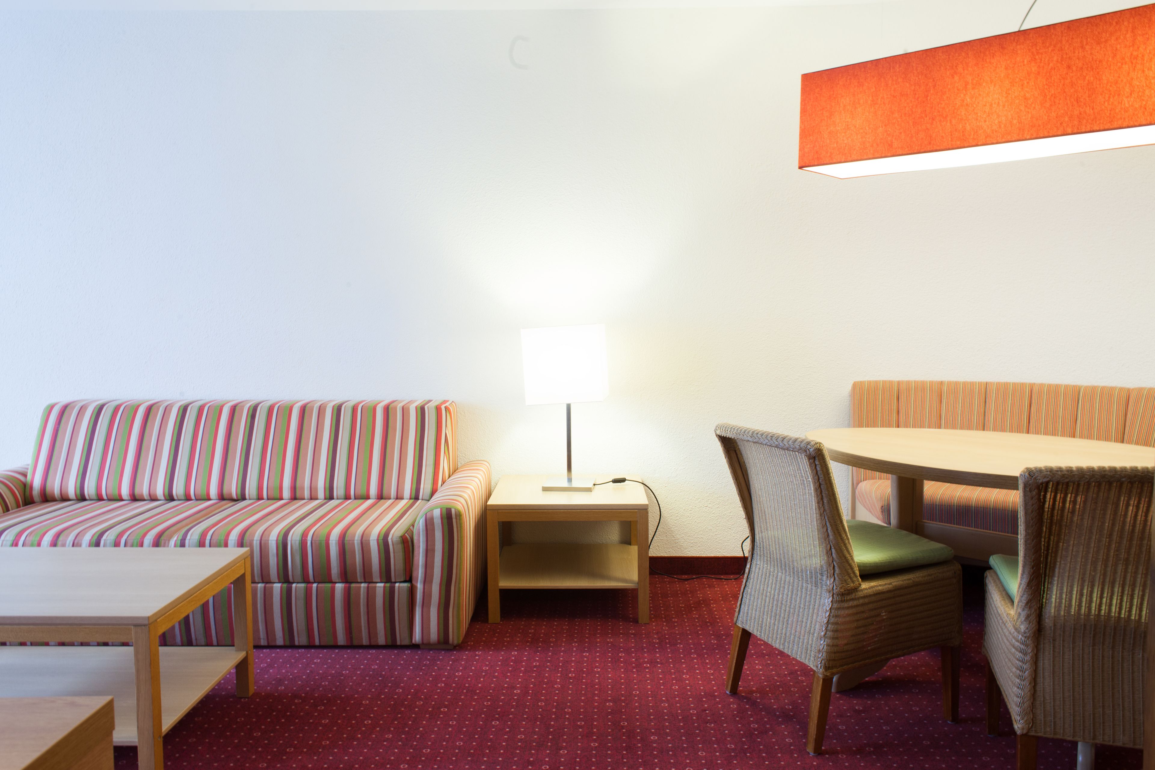 A room with a striped sofa, a small table, a lamp, and a chair.