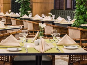A restaurant setting with tables set for dining, featuring green placemats, folded napkins, and clear glassware. - Sonesta Hotel Tower & Casino Cairo (Cairo)