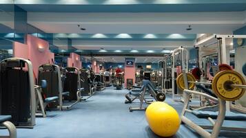 Ein Fitnessraum mit verschiedenen Trainingsgeräten, darunter Kraftgeräte und Kurzhanteln, sowie eine große Trainingskugel.