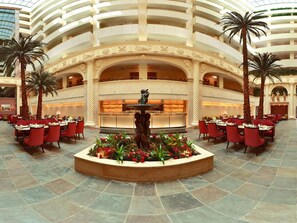 A hotel lobby with a central fountain, multiple dining areas with red chairs, and a high ceiling with balconies. - Sonesta Hotel Tower & Casino Cairo (Cairo)