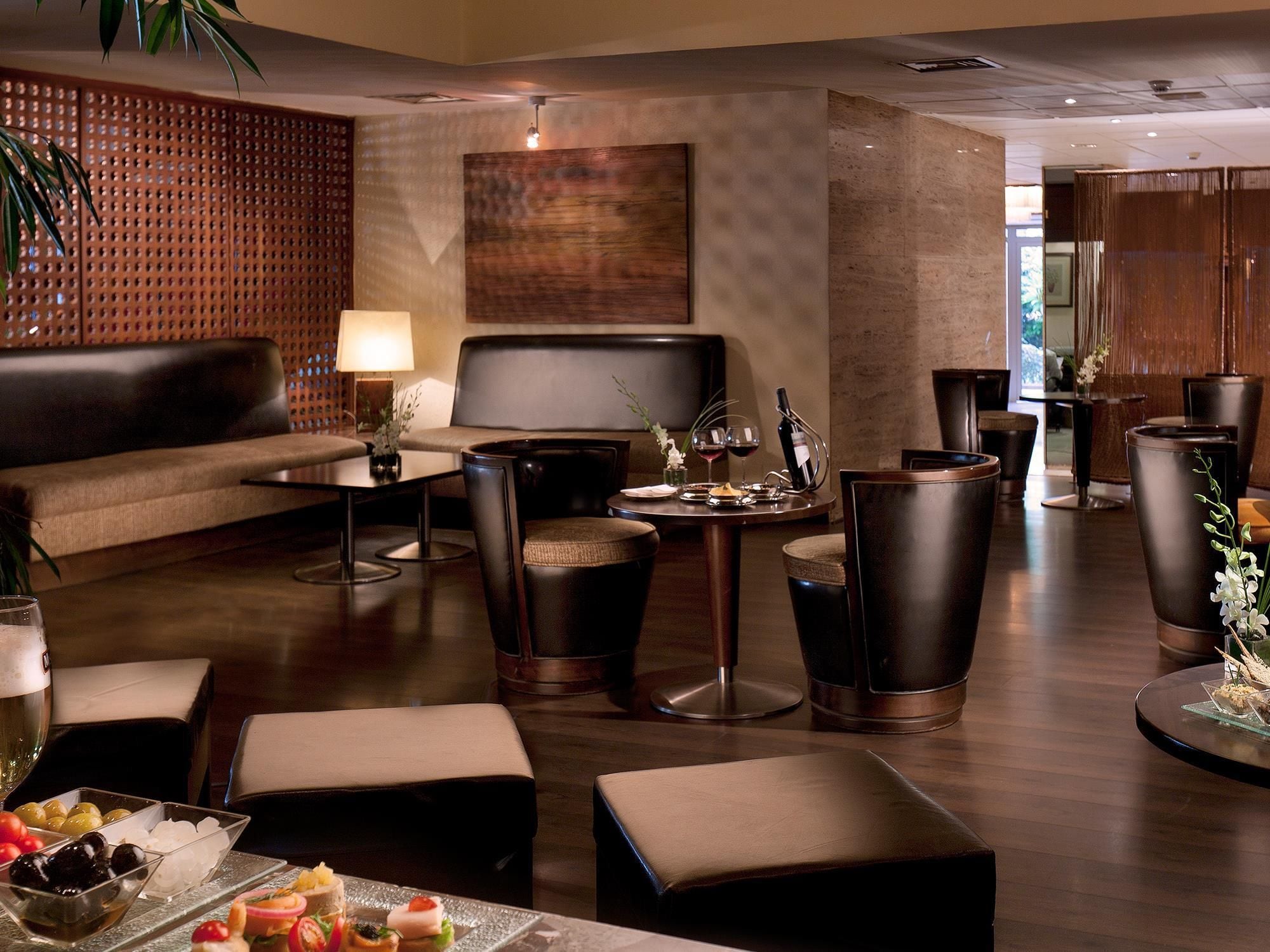 Un moderno espacio lounge con asientos de cuero, una mesa de centro y una zona de bar con taburetes.