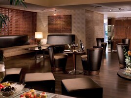 Un moderno espacio lounge con asientos de cuero, una mesa de centro y una zona de bar con taburetes.