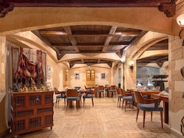 Un comedor con mesas y sillas de madera, una vitrina decorativa y paredes de piedra.
