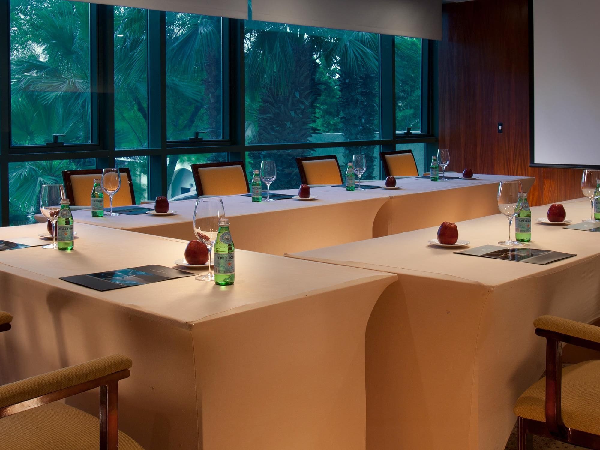 A conference room with a long table, chairs, and a projector screen.