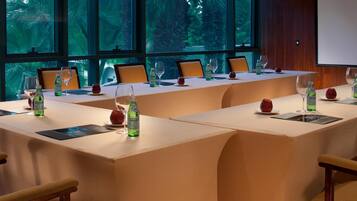 A conference room with a long table, chairs, and a projector screen.