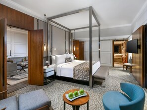 A hotel room with a four-poster bed, a sitting area with a table and chairs, a television, and a bathroom visible through an open door. - Sonesta Hotel Tower & Casino Cairo (Cairo)