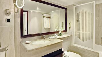 A modern bathroom with a large mirror, a sink, a toilet, and a shower area.