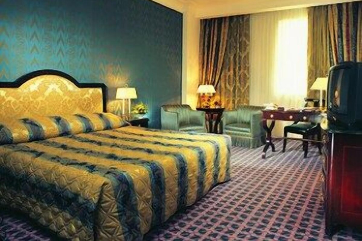 Una habitación de hotel con una cama grande, un escritorio, una silla y un televisor.
