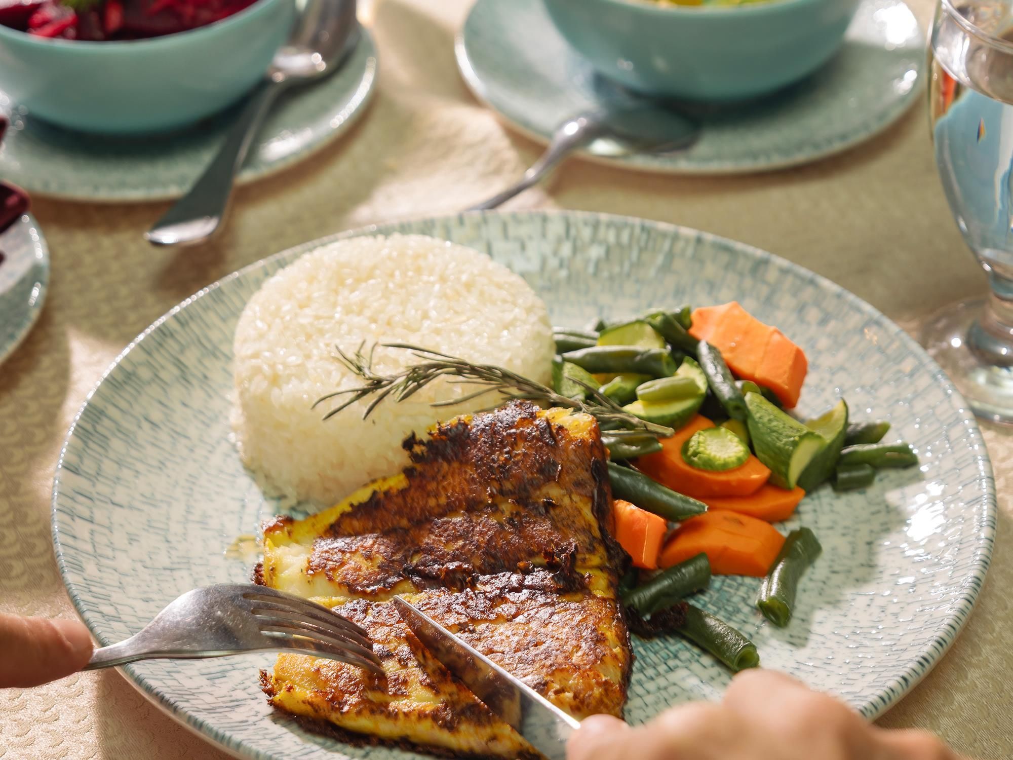 A plate with rice, grilled fish, and mixed vegetables.