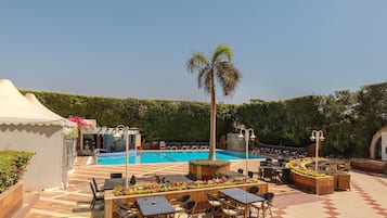 A poolside area with a swimming pool, lounge chairs, and tables.