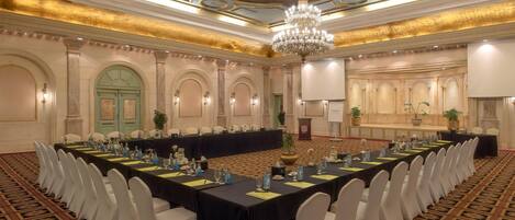 A conference room with a long table, white chairs, and a chandelier.