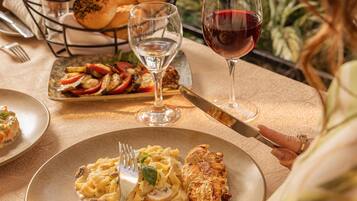 Ein Esstisch mit einer Pasta-Anordnung, gegrilltem Hähnchen und einem Glas Rotwein.