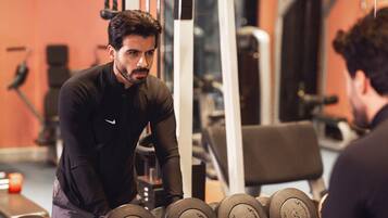 A gym with weightlifting equipment and a person exercising.