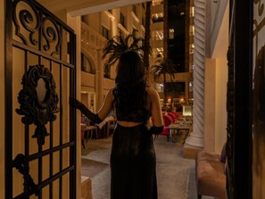 Una persona entrando a un edificio con puertas de metal decoradas y una escalera.