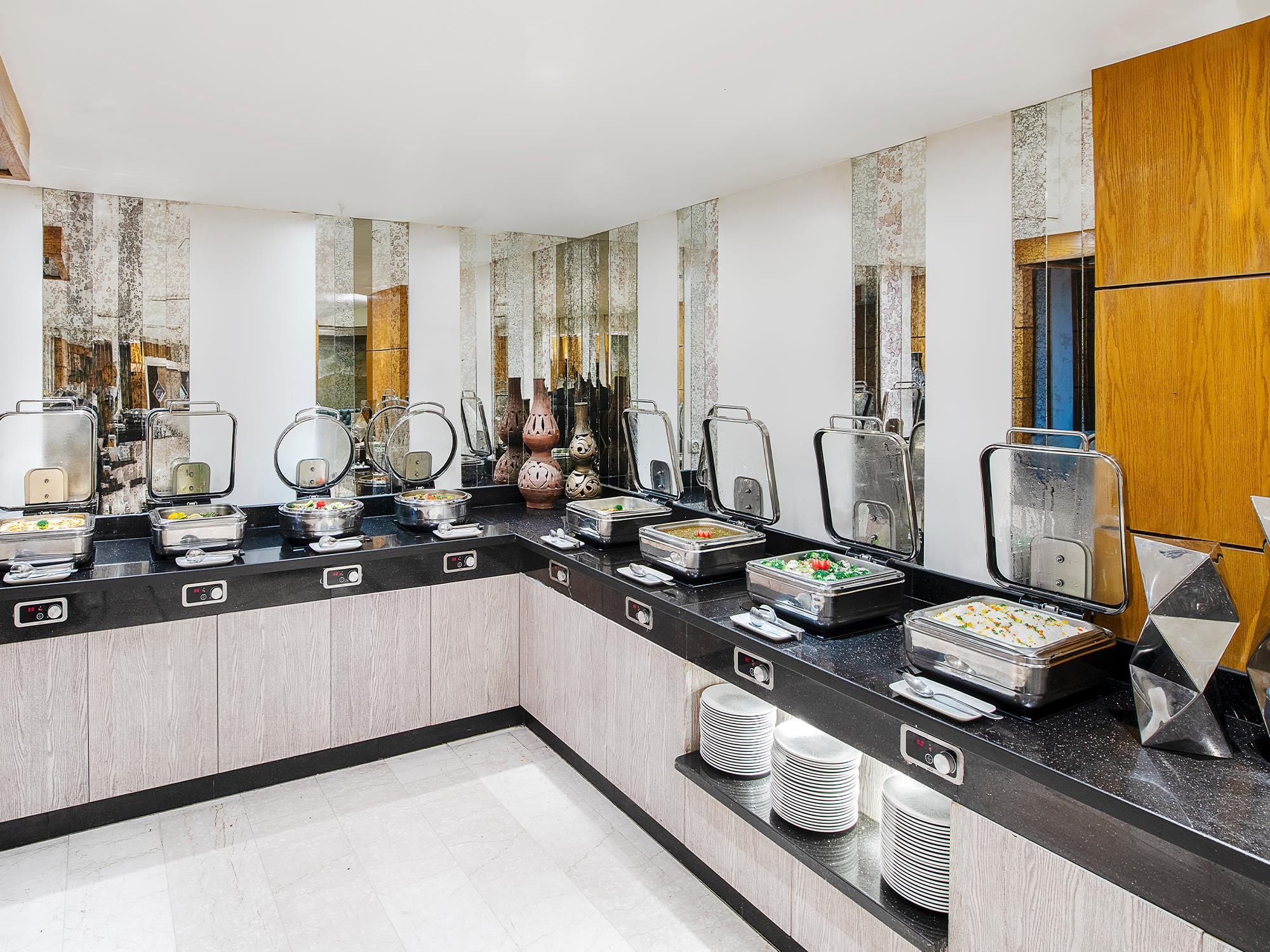 A modern bathroom with a black countertop, multiple mirrors, and a variety of toiletries and amenities.
