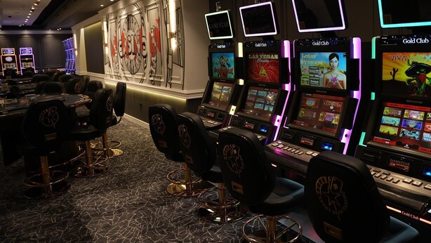 A casino floor with gaming machines, chairs, and a wall with a large logo. - Sonesta Hotel Tower & Casino Cairo (Cairo)