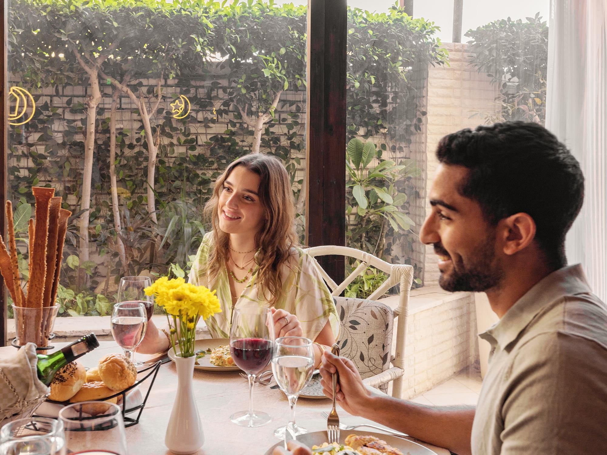 A dining table with food, drinks, and a vase of flowers.