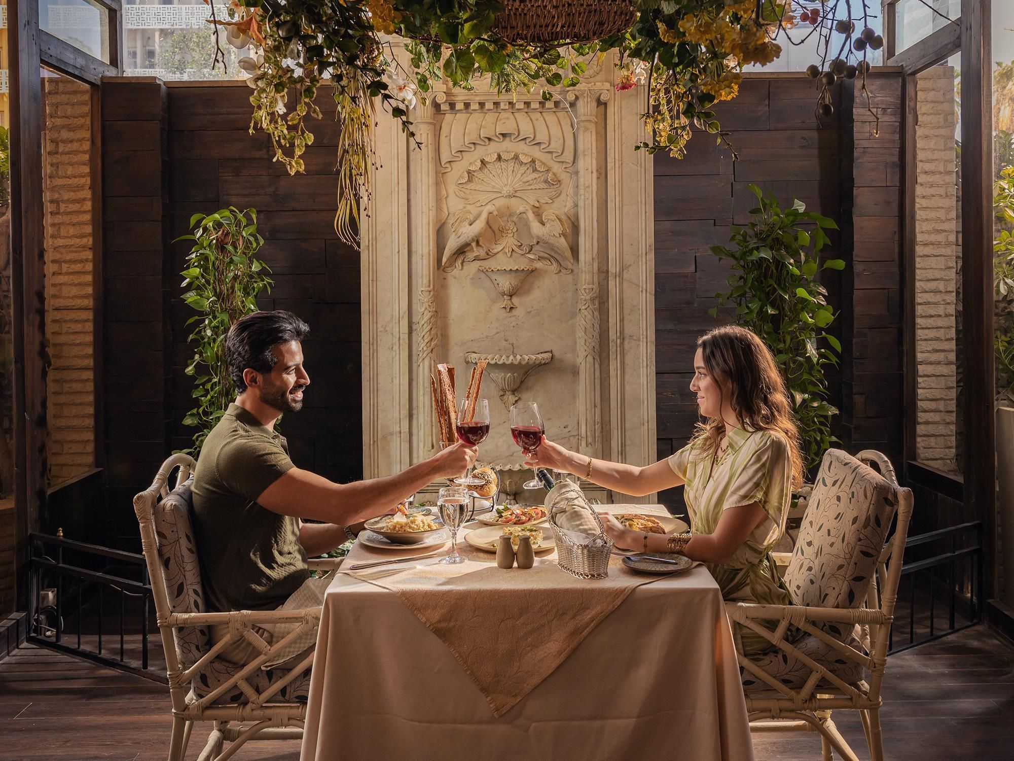 Una mesa de comedor con mantel blanco, rodeada de sillas de mimbre, dispuesta para dos personas.