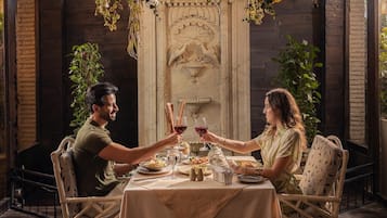 Una mesa de comedor con mantel blanco, rodeada de sillas de mimbre, dispuesta para dos personas.