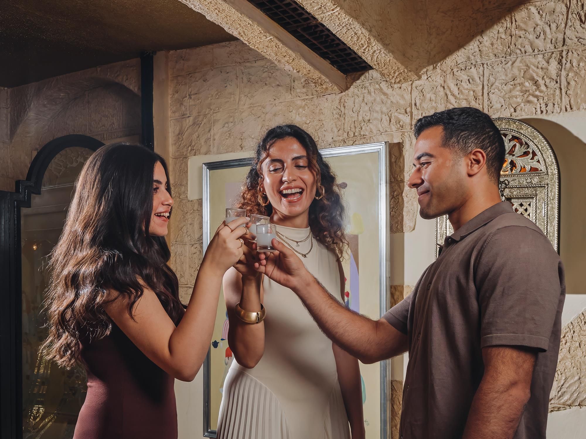 Three people in a room with a stone wall and a door.