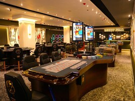 Un casinò con diverse tavole da blackjack, slot machine e una roulette.