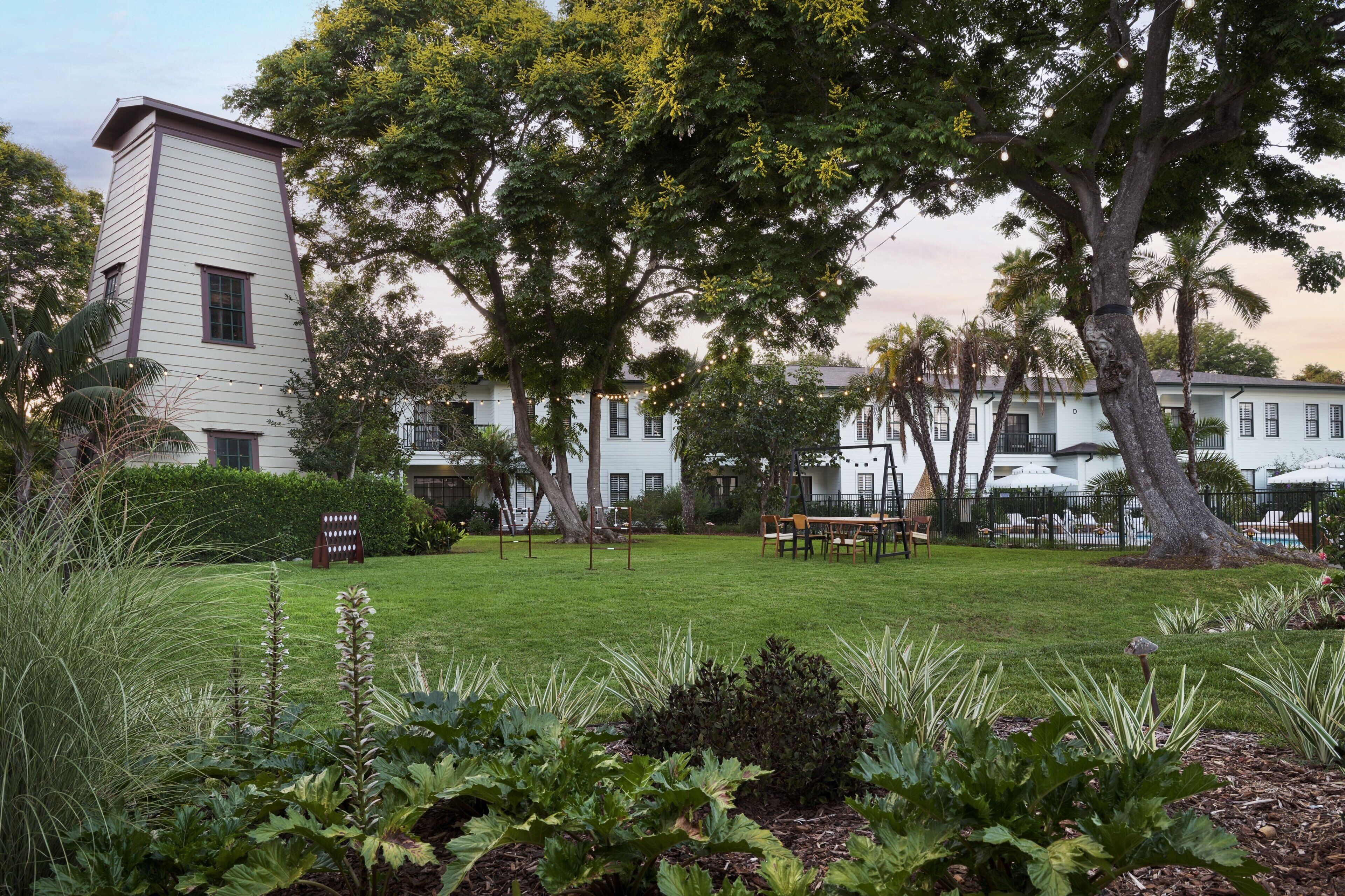 A large white building with a flat roof, surrounded by a well-maintained lawn and several trees.