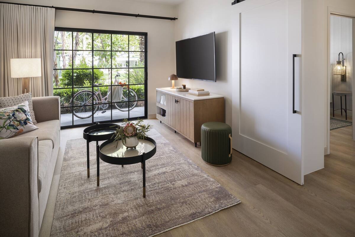 A modern living room with a sofa, coffee table, and a TV mounted on the wall.