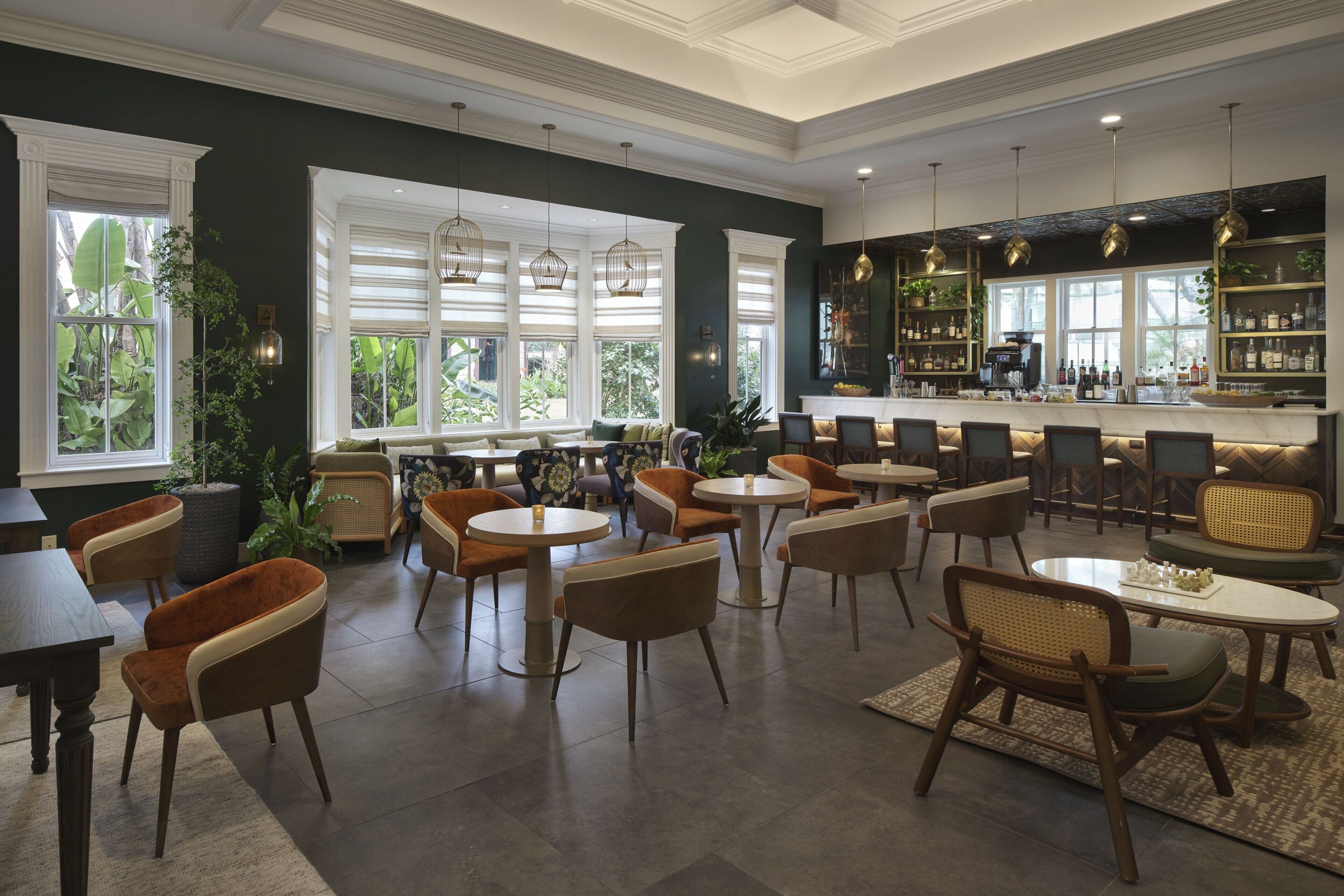 Un vaste espace intérieur aménagé avec différents types de sièges, notamment des tables et des chaises rondes, ainsi qu’un bar doté d’étagères remplies de bouteilles et de verres.