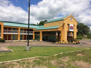 A motel with a green roof, a parking lot, and a sign for Fairbridge Inn.